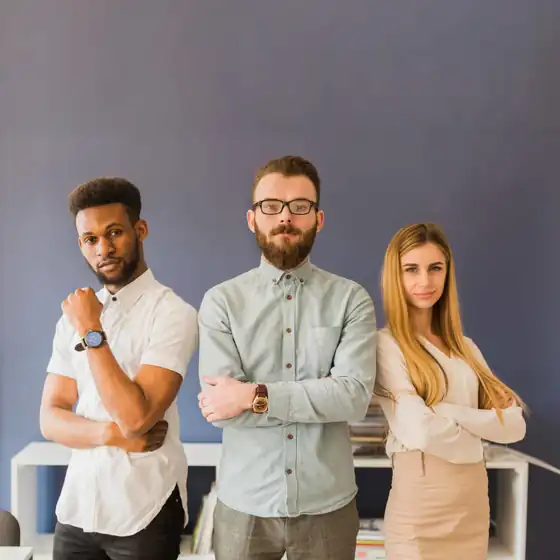 Three confident marketing professionals standing with arms crossed in a modern office